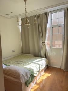 a bedroom with a bed and a window with a chandelier at Encanto Histórico 9 in Avilés