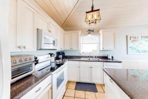 a kitchen with white cabinets and a chandelier at Blue Marlin in Gulf Shores +15 photos