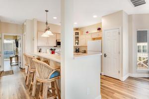 a kitchen with white cabinets and a bar with stools at Beach Haven by Meyer Vacation Rentals in Gulf Shores
