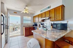 a kitchen with wooden cabinets and a large window at Beautiful condo with shared pools full kitchen private washer dryer in Gulf Shores +16 photos