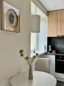 a white table in a kitchen with a vase with flowers at Sandstone Residence - Modern Apartment - 5 min Walk to Beach in Liepāja