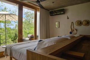 a bedroom with a bed and a large window at El Guayacan in Zipolite