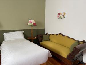 a bedroom with a bed and a couch and a lamp at Cèsa Cusenza in Rocca Pietore
