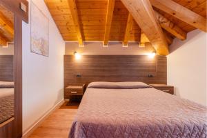 a bedroom with two beds and wooden ceilings at CROSINA HOLIDAY - Casa Al Ponte in Ledro