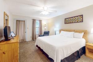 a bedroom with a large white bed and a television at Sea Oats E106 in Gulf Shores +24 photos