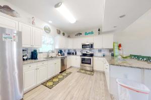 a kitchen with white cabinets and a refrigerator at Sun & Sea in Gulf Shores