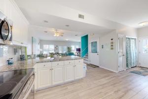 a large kitchen with white cabinets and wood floors at Sun & Sea in Gulf Shores