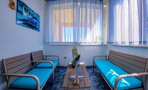 a room with two benches and a table and windows at Mendy Sea View Apartment in Kaštela