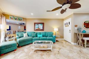 a living room with a blue couch and a ceiling fan at Gulfside Townhomes 23 in Gulf Shores