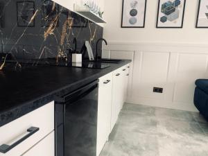 a kitchen with white cabinets and a black counter top at Mazury Apartamenty wodne tarasy Blue - Ruś in Ruś