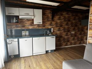 a kitchen with white appliances and a brick wall at Logement avec clim - thé, café et choco dispo in Oye-Plage +9 photos
