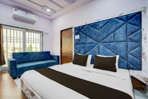 a bedroom with a large bed and a blue couch at Hotel O DELIGHT INN in Chandrapur