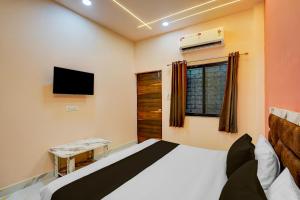 a bedroom with a bed and a tv and a window at Hotel O DELIGHT INN in Chandrapur +21 photos