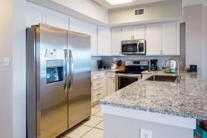 a stainless steel refrigerator in a kitchen with white cabinets at Tidewater 601 in Orange Beach