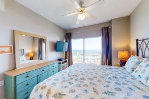 a bedroom with a bed with a dresser and a mirror at Tidewater 601 in Orange Beach