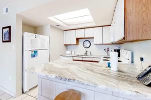 a kitchen with white cabinets and a marble counter top at Beachfront Condo with Gulf View Balcony WiFi AC & Shared Pools in Orange Beach