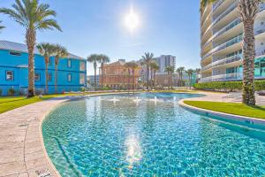 a large swimming pool with palm trees and a building at Bella Luna 1203 in Orange Beach