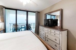 a bedroom with a television and a dresser with a mirror at Gulf-front corner condo with wraparound balcony pools beach access in Orange Beach +17 photos