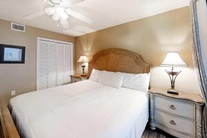 a bedroom with a white bed with two night stands and two lamps at Gulf-front corner condo with wraparound balcony pools beach access in Orange Beach