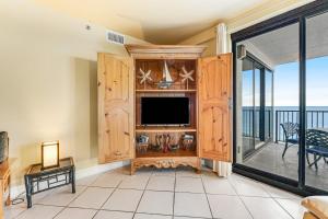 a living room with a tv and a balcony at Broadmoor 604 in Orange Beach