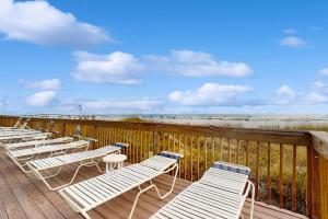 a row of white lounge chairs on a deck near the beach at Broadmoor 604 in Orange Beach