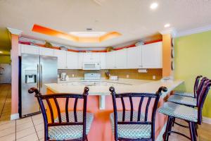 a kitchen with a counter and three chairs in it at Phoenix West 502 in Orange Beach