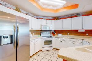 a kitchen with white cabinets and a stainless steel refrigerator at Phoenix West 502 in Orange Beach +34 photos