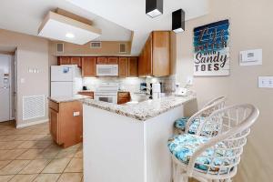 a kitchen with a counter and two stools in it at Pelican Pointe 302 in Orange Beach