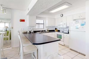a kitchen with white cabinets and a black counter top at Fantastic condo with elevator WiFi & central AC - beachfront Location in Orange Beach +28 photos