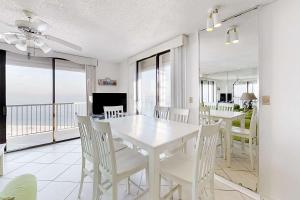 a white dining room with a white table and chairs at Fantastic condo with elevator WiFi & central AC - beachfront Location in Orange Beach
