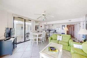 a living room with a green couch and a tv at Fantastic condo with elevator WiFi & central AC - beachfront Location in Orange Beach