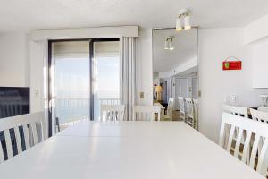 a white dining room with a large white table at Fantastic condo with elevator WiFi & central AC - beachfront Location in Orange Beach