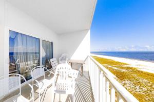 a balcony with white chairs and a view of the ocean at Tidewater 908 in Orange Beach