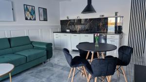 a living room with a green couch and a table and chairs at Mazury Apartamenty wodne tarasy Blue - Ruś in Ruś +28 photos
