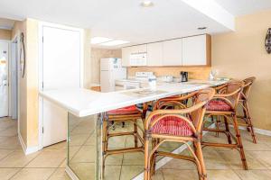 a kitchen with wooden chairs and a white counter top at Wind Drift 311S in Orange Beach