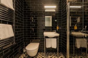 a black tiled bathroom with a toilet and a sink at ASKA Holt in Reykjavík +11 photos