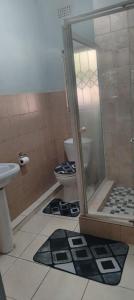 a bathroom with a toilet and a glass shower at Cozy suburban guest house - Durban in Verulam