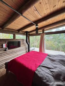 a bedroom with a large bed with a red blanket at Cabana rustica logcabin com banheira aquecida in Osório