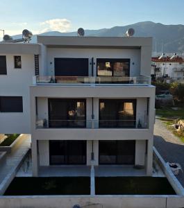 a large white building with windows and mountains in the background at Peralun Lux Apartments in Nea Peramos