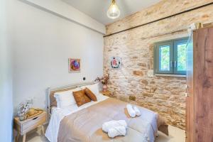 a bedroom with a bed and a stone wall at Kalamoti Suites in Kalamoti