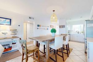 a kitchen with a wooden table and white chairs at Jubilee Landing 302 in Orange Beach