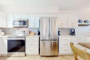 a kitchen with white cabinets and a stainless steel refrigerator at Jubilee Landing 302 in Orange Beach +23 photos