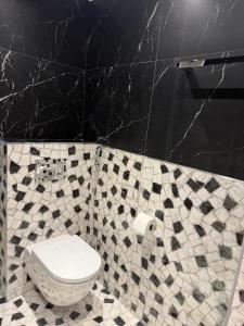 a bathroom with a toilet and a tiled wall at Dorćol Center Suites in Belgrade