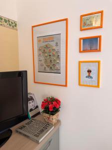 a desk with a laptop and a monitor and a wall with pictures at La Casa di Lili in Nardò