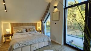 a bedroom with a bed and a large window at Bosarosa Forest & Lake Villa z jacuzzi wanna SPA in Laski Małe +80 photos
