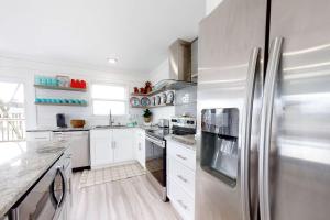 a kitchen with white cabinets and a stainless steel refrigerator at Mermaid Tales in Dauphin Island +15 photos