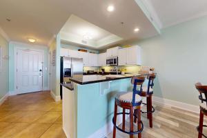 a kitchen with white cabinets and bar stools at Beachfront condo with pool private balcony and laundry in Dauphin Island