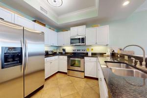 a kitchen with white cabinets and a stainless steel refrigerator at Beachfront condo with pool private balcony and laundry in Dauphin Island +19 photos