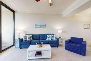 a living room with a blue couch and two chairs at Holiday Isle 618 in Dauphin Island