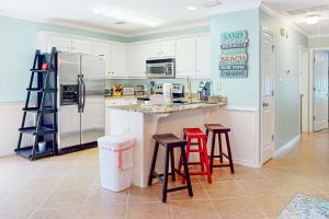 a kitchen with a counter with stools and a refrigerator at Sunset Breeze #4 in Dauphin Island